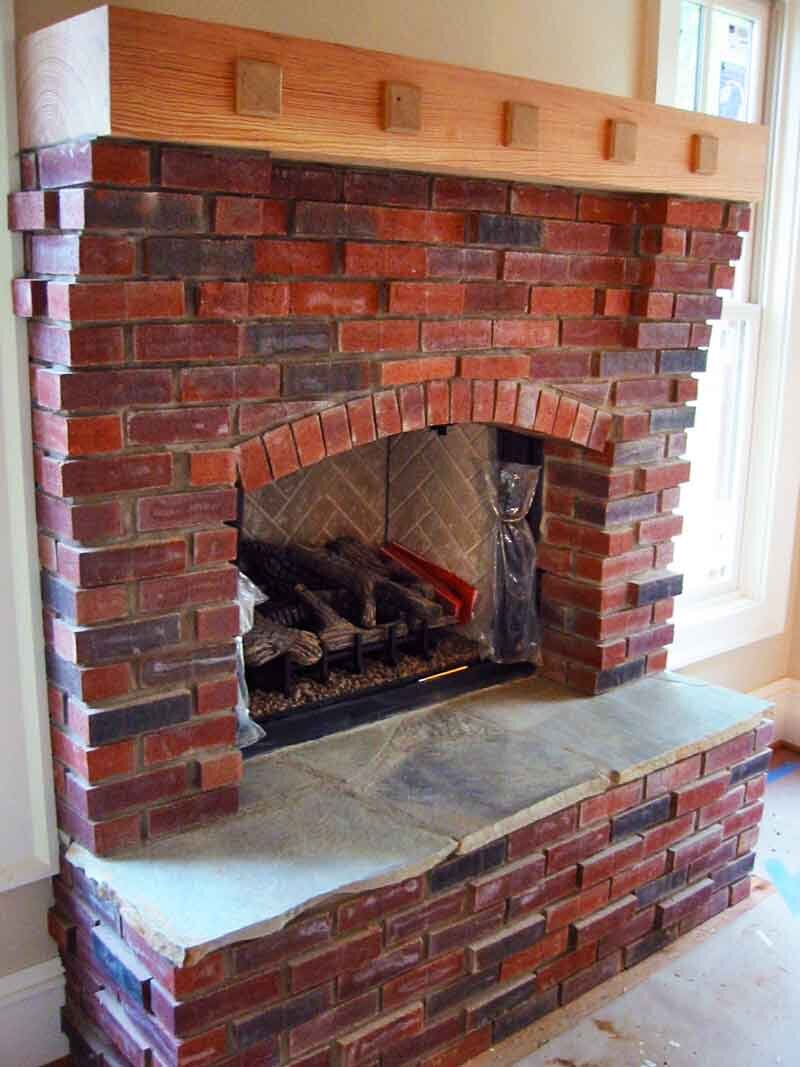 inside red brick fireplace wooden mantle