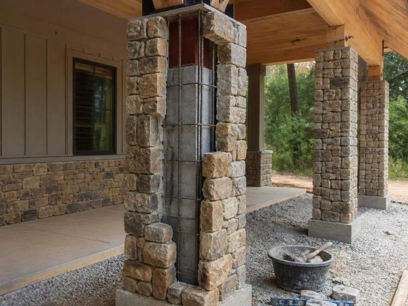 Natural stone veneer being installed around a reinforced masonry column supporting a covered patio in Auburn, Alabama.