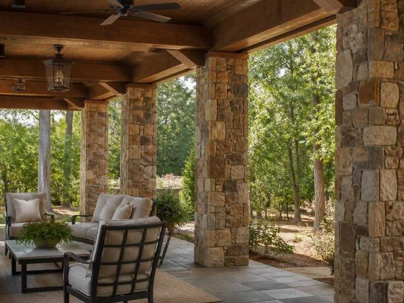 Natural stone columns supporting exposed wood beams over a covered patio in Auburn, Alabama.
