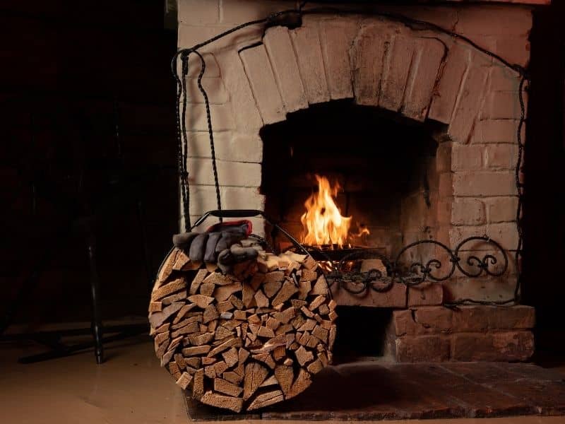 Stone fireplace with firewood stacked beside the hearth in a cozy indoor setting
