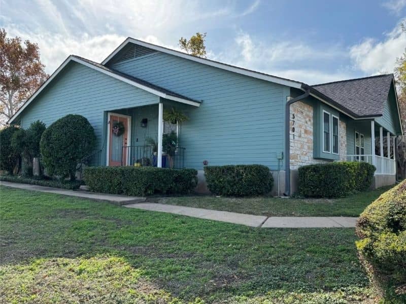Teal home with stone exterior accents and a landscaped front yard