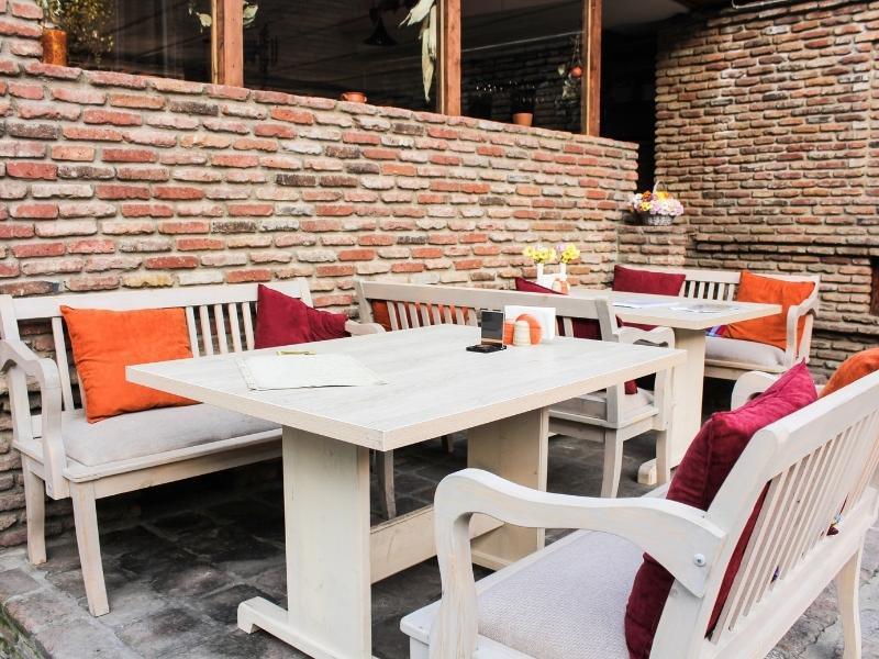 Brick patio divider wall separating outdoor restaurant dining areas with brick pavers and landscaped surroundings
